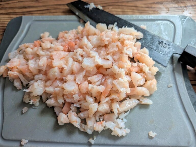 Würzige Lachs-Garnelen-Pflanzerl Cajun Style 5 Frische Garnelen für die Pflanzerl-Masse fein gehackt auf einem Schneidebrett