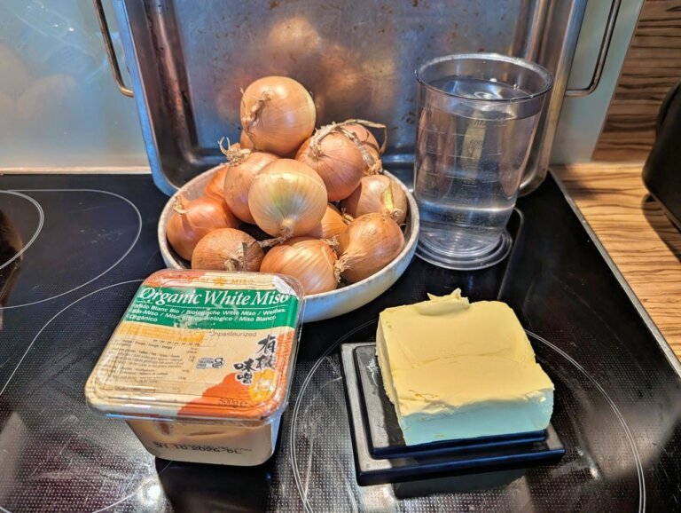 Zutaten fu00fcr Miso-Zwiebeln: Gelbe Zwiebeln, helle Miso-Paste, Butter und Mirin auf einer Arbeitsflu00e4che