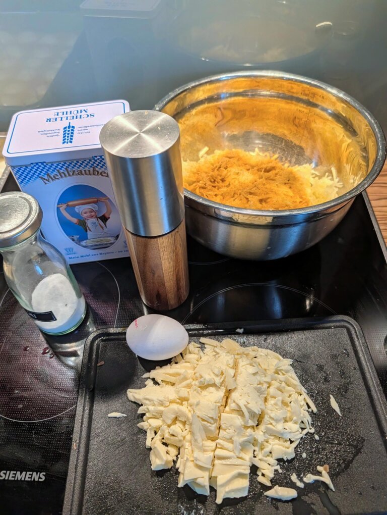 Zutaten fu00fcr Kartoffel-Mozzarella-Ru00f6sti: Festkochende Kartoffeln, Mozzarella-Block, Butterschmalz und Gewu00fcrze auf der Arbeitsflu00e4che
