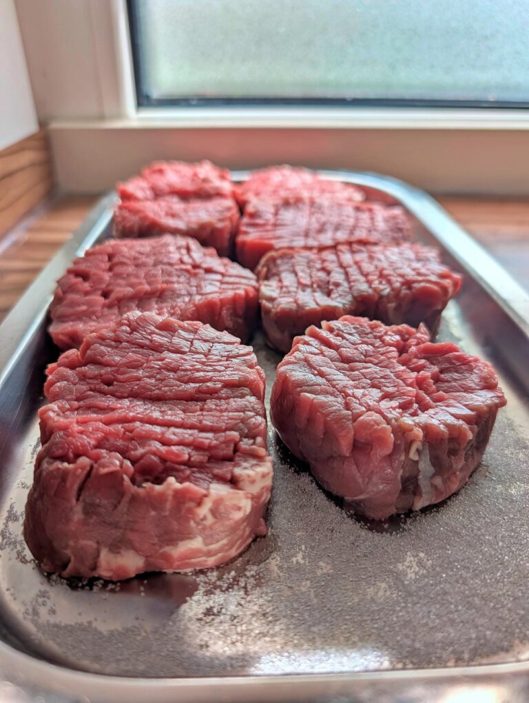 Heiß-Kaltes Steak Tatar 6 Ein rohes Steak liegt in einer Form auf einem Bett aus Salz und Zucker zur Beizung.