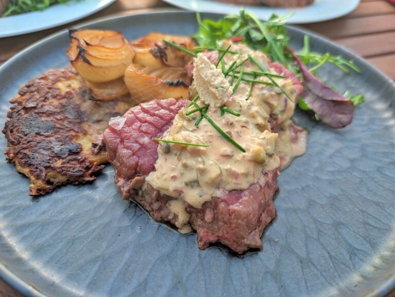Heiß-Kaltes Steak Tatar 9 Querformat-Ansicht eines fertig angerichteten Steak Tatars auf einem dunklen Teller.